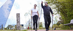 Zwei Personen laufen mit Nordic Walking Stöcken.